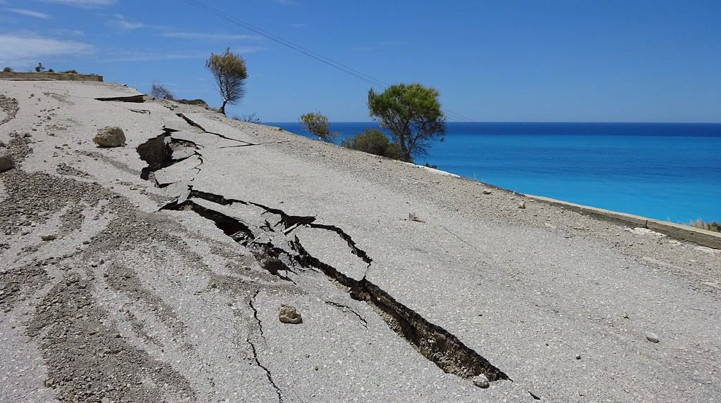 Danni causati dal terremoto a una ripida strada costiera che conduce alla spiaggia di Gialou sull'isola di Lefkada, Grecia