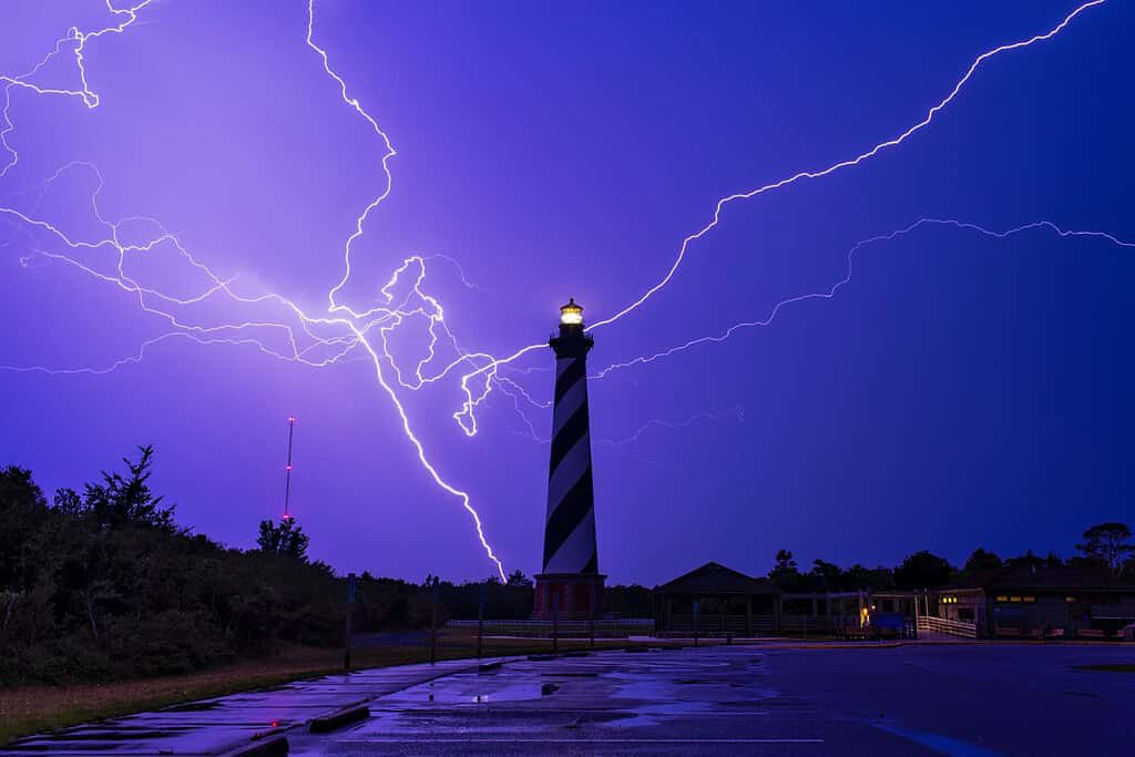 Un incredibile fulmine cade dietro il faro di Cape Hatteras, Outer Banks, Carolina del Nord.