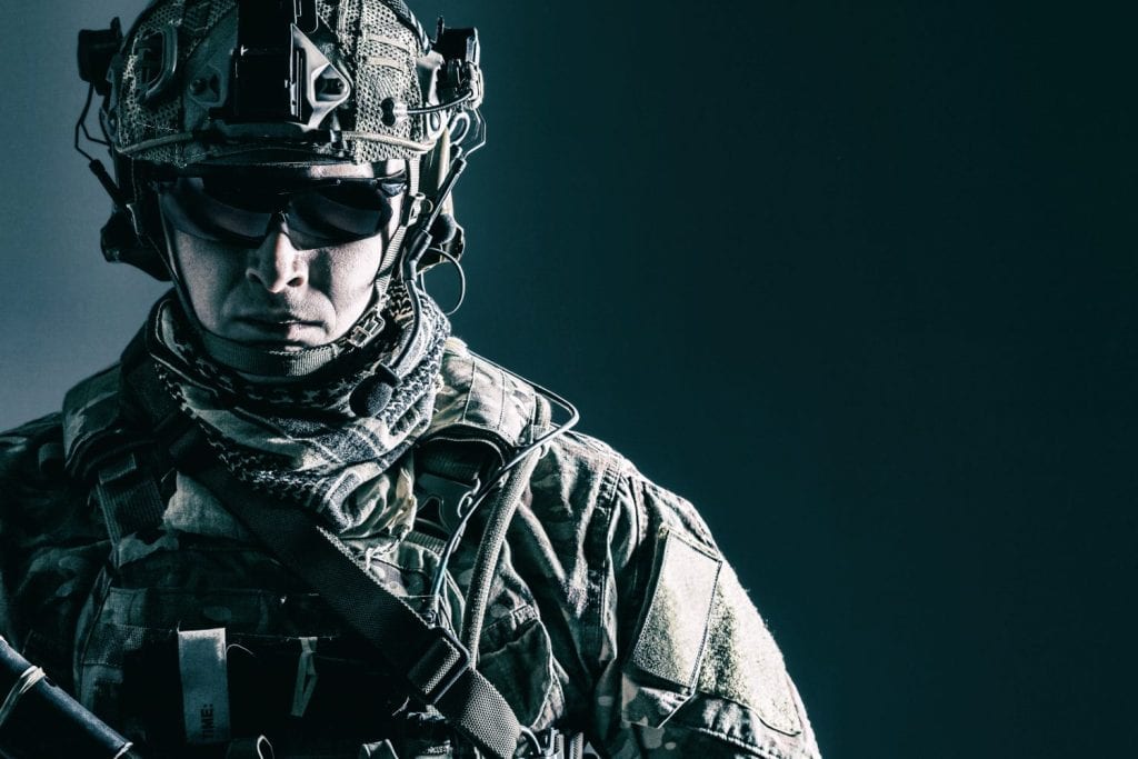 Membro d'élite dei ranger dell'esercito americano con casco da combattimento e occhiali scuri. Ripresa in studio, sfondo nero scuro, sguardo alla telecamera, contrasto scuro
