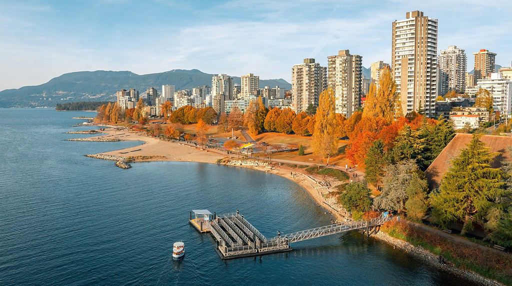 Immagine aerea panoramica del West End di Vancouver e della spiaggia con edifici e montagne di North Vancouver sullo sfondo
