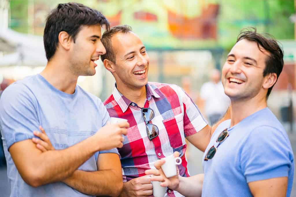Tre amici che parlano e si divertono bevendo un caffè all'aperto