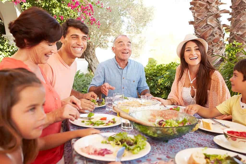 Famiglia multigenerazionale che si gode il pasto sulla terrazza insieme