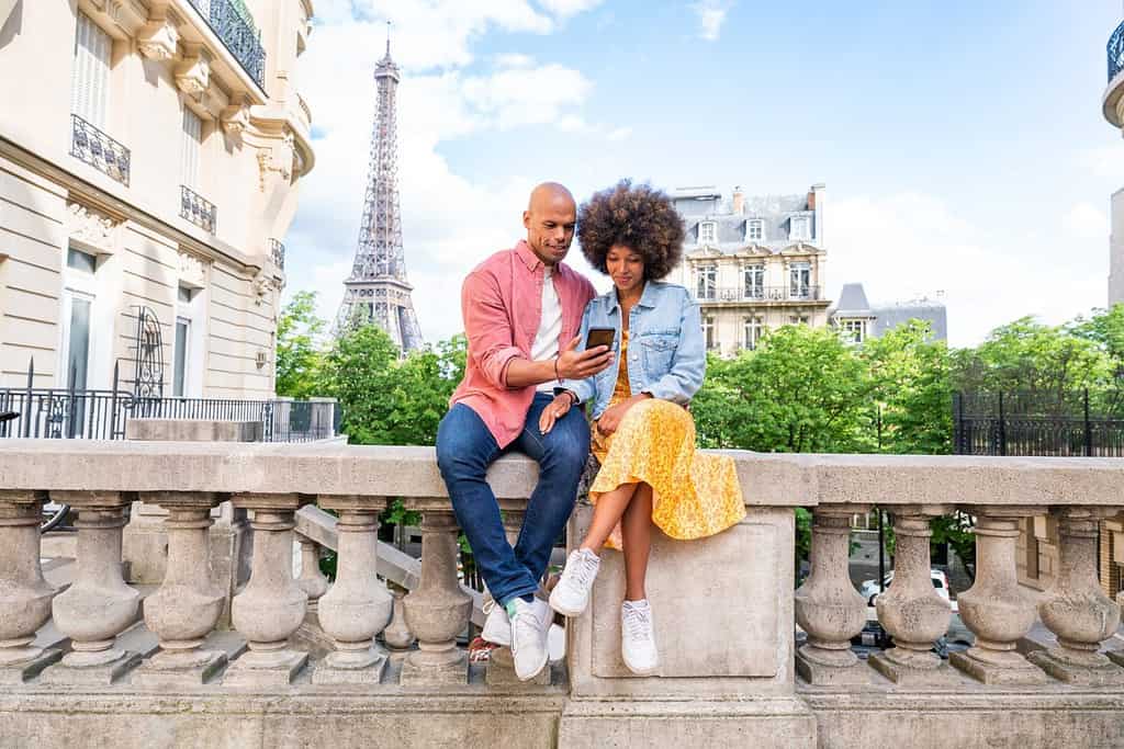 Coppia nera allegra e felice innamorata in visita al centro di Parigi e alla Torre Eiffel - Turisti afroamericani che viaggiano in Europa e si frequentano all'aperto