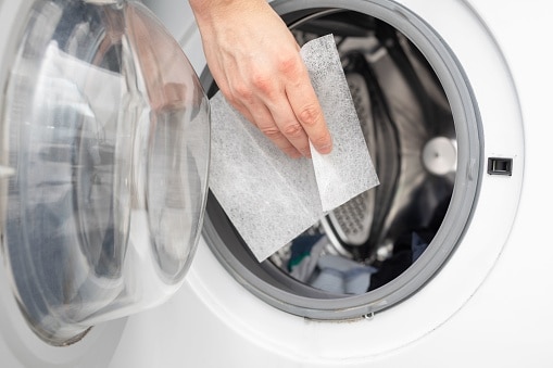 Lasciare cadere a mano i fogli aromatici dell'asciugatrice in una lavatrice