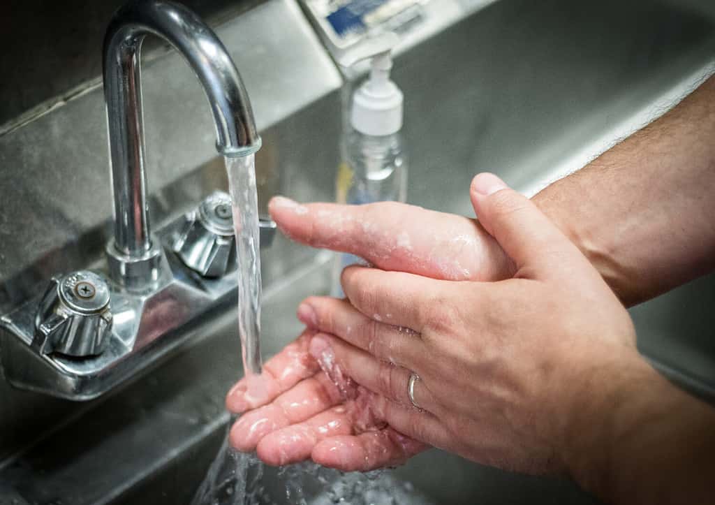 Lavarsi le mani; lavaggio con acqua e sapone nel lavello in acciaio inox.