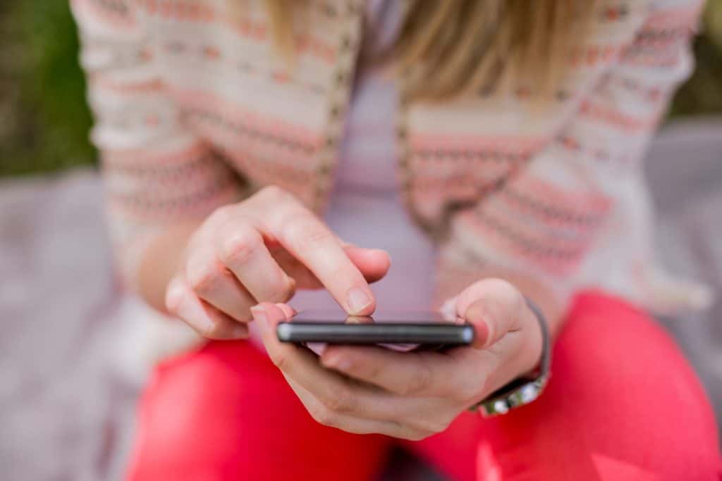 primo piano del dispositivo di telefonia mobile tenuto in mano da una donna: concentrarsi sul gioco del lavoro delle ragazze, leggere il tipo di testo della chiamata sul concetto di smartphone, le telecomunicazioni della tecnologia dell'innovazione degli adolescenti. chat di risposta per adolescenti